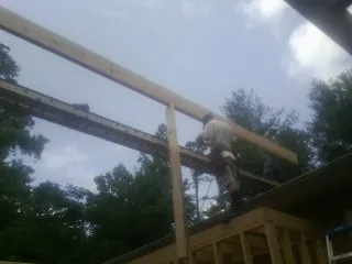 Carpenter setting a ridge beam over a new addition frame — Ice Dam Removal by Roofing Brothers in Wells