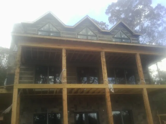 Dormers and porch framing on a large log home under construction — Roof Coating work by our crew in Wells